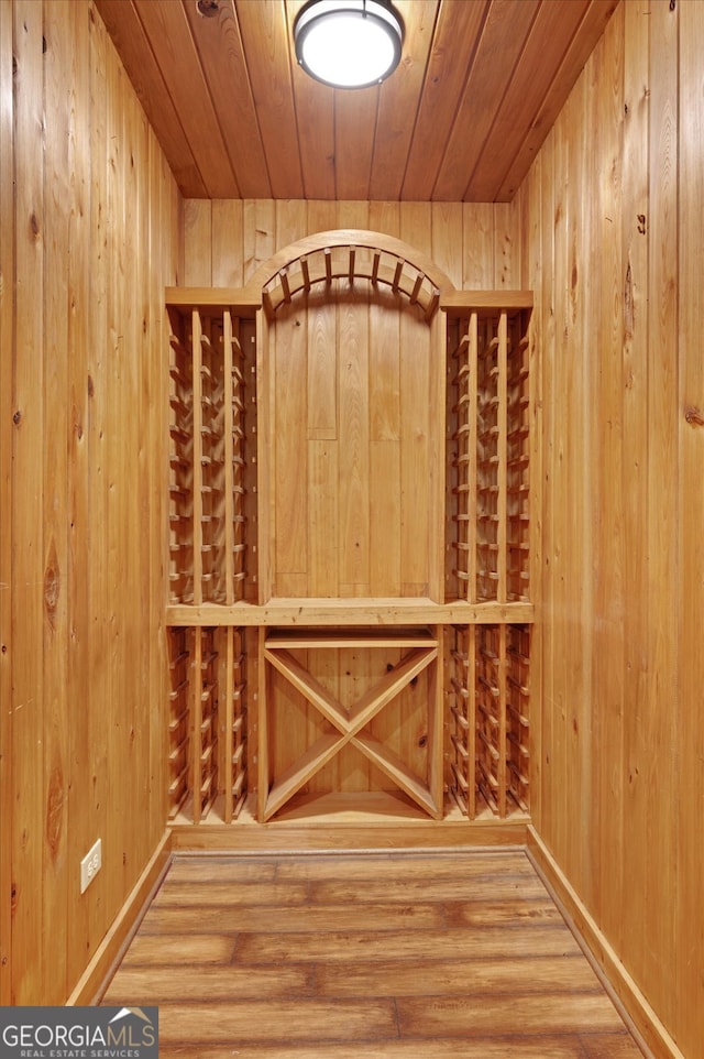 wine room with hardwood / wood-style flooring, wooden walls, and wooden ceiling