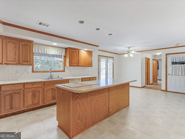 kitchen featuring ceiling fan, sink, decorative backsplash, ornamental molding, and a center island