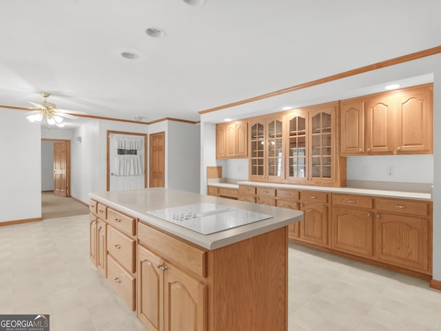 kitchen with black electric cooktop, ceiling fan, a center island, and ornamental molding