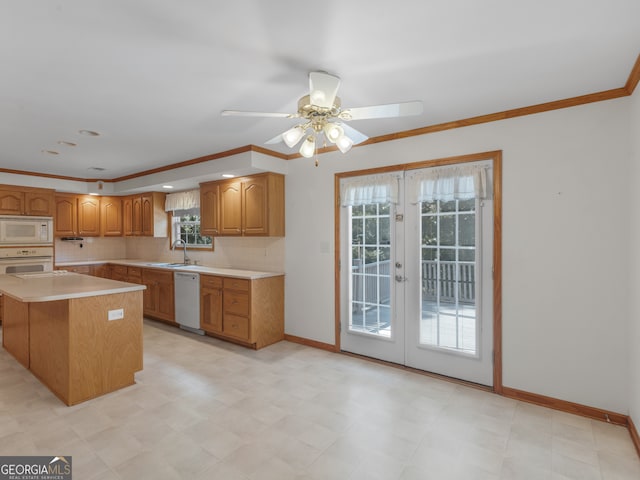 kitchen with ceiling fan, white appliances, crown molding, a kitchen island, and sink