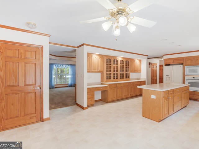 kitchen featuring a kitchen island, ceiling fan, built in desk, white appliances, and crown molding