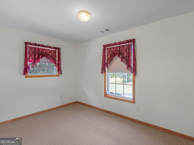 spare room featuring a textured ceiling and carpet