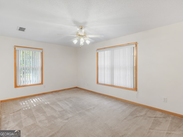 spare room featuring ceiling fan, a textured ceiling, and light carpet