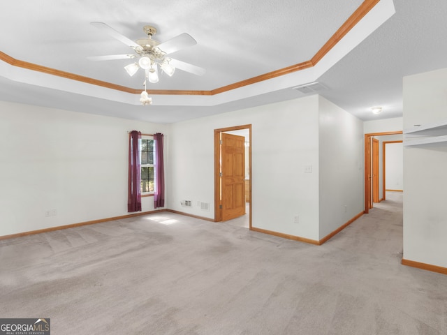 carpeted empty room with ceiling fan, a textured ceiling, a raised ceiling, and crown molding