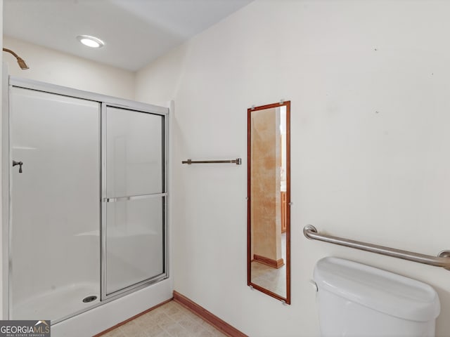 bathroom featuring a shower with door and toilet