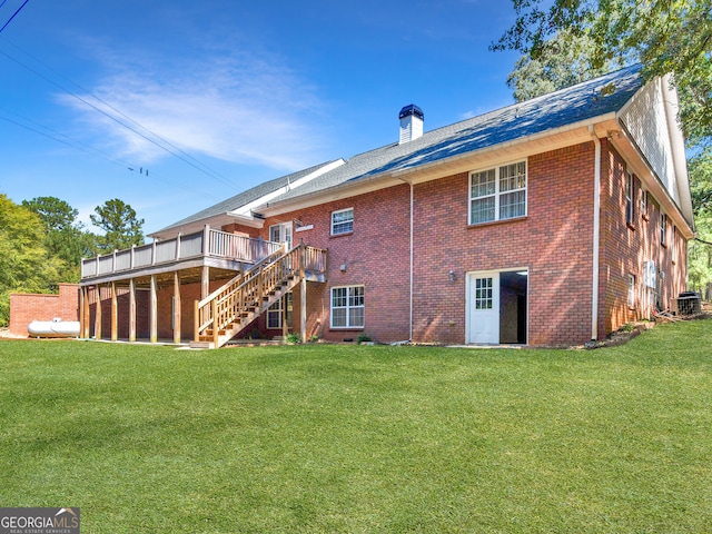 rear view of house with central AC, a wooden deck, and a lawn