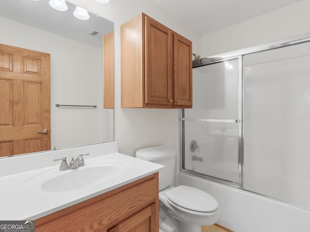 full bathroom with vanity, bath / shower combo with glass door, and toilet