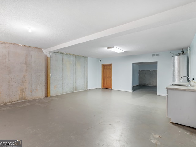 basement with water heater, sink, and a textured ceiling