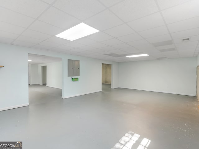 basement with electric panel and a paneled ceiling