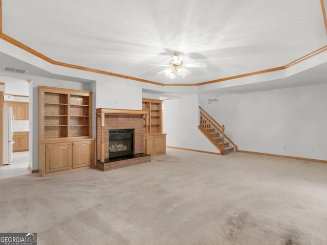 unfurnished living room with a brick fireplace, ceiling fan, ornamental molding, light colored carpet, and a textured ceiling