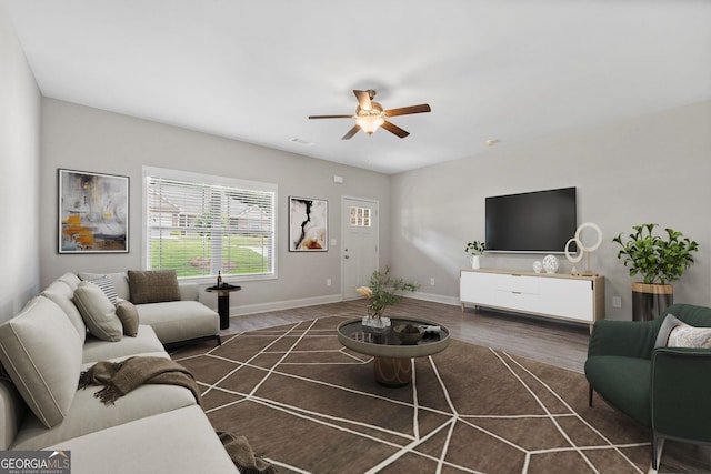 living room featuring dark wood-type flooring and ceiling fan