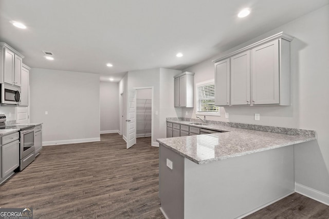 kitchen with dark wood-type flooring, sink, light stone counters, kitchen peninsula, and stainless steel appliances