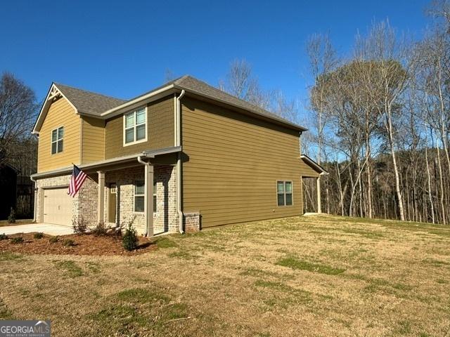 view of side of home featuring a garage and a lawn