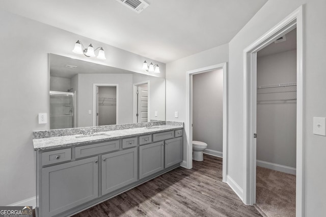 bathroom featuring vanity, hardwood / wood-style flooring, a shower with door, and toilet