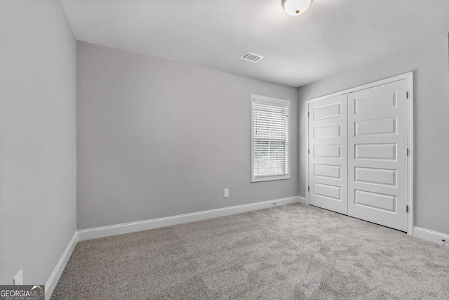 unfurnished bedroom with light colored carpet and a closet