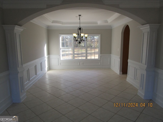 unfurnished dining area featuring light tile patterned floors, arched walkways, a raised ceiling, a chandelier, and a decorative wall