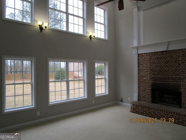 unfurnished living room featuring carpet, ceiling fan, a healthy amount of sunlight, and a fireplace