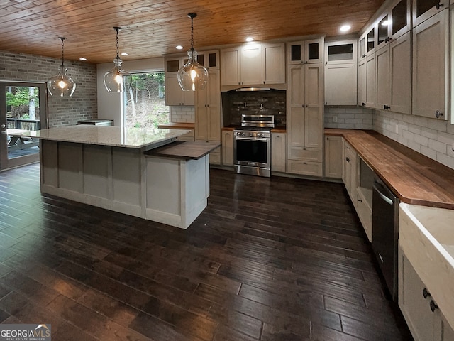 kitchen featuring appliances with stainless steel finishes, hanging light fixtures, dark wood-type flooring, and wooden counters