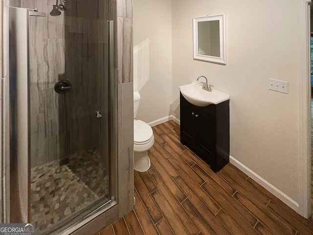 bathroom with walk in shower, vanity, toilet, and wood-type flooring