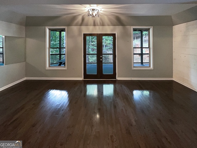 unfurnished room with an inviting chandelier, french doors, and dark hardwood / wood-style flooring