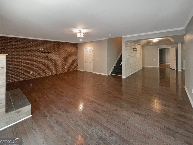 unfurnished living room with ornamental molding, dark hardwood / wood-style floors, and brick wall