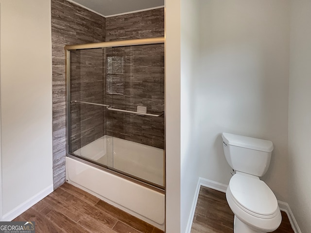 bathroom featuring bath / shower combo with glass door, hardwood / wood-style floors, and toilet