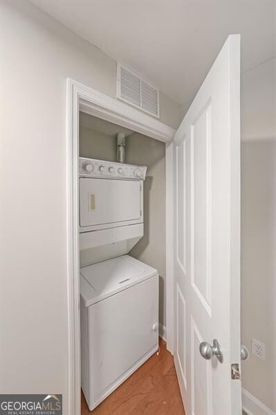 clothes washing area with stacked washer / dryer and baseboards