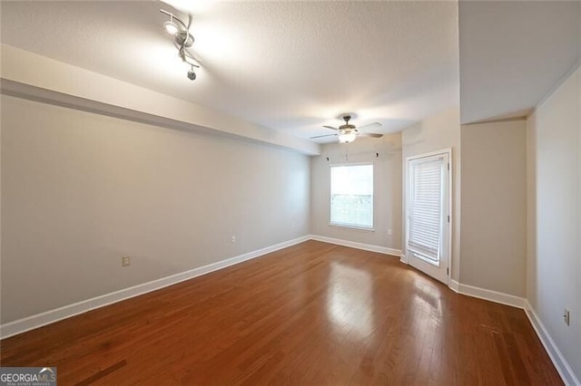 empty room with ceiling fan, wood finished floors, and baseboards