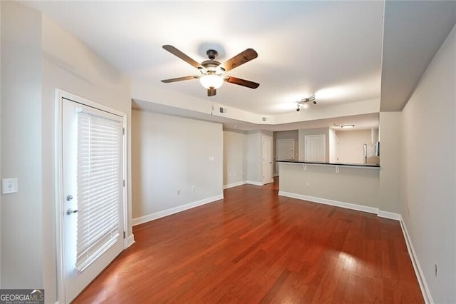 unfurnished living room with ceiling fan, dark wood-style floors, and baseboards