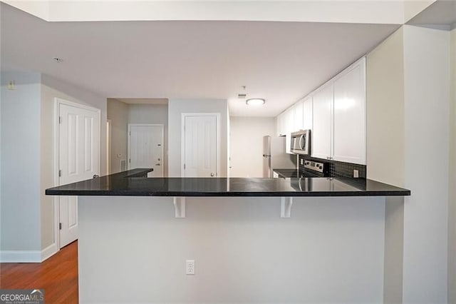 kitchen featuring stainless steel appliances, a breakfast bar, a peninsula, and baseboards