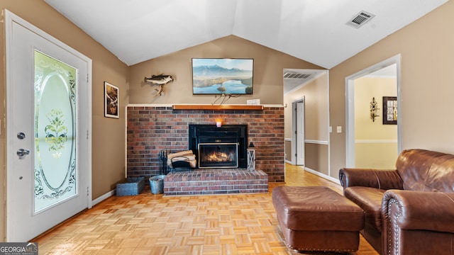 living room featuring light parquet flooring, lofted ceiling, and a brick fireplace