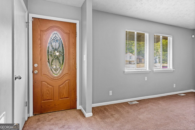 carpeted foyer with a textured ceiling