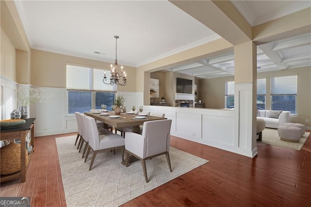 dining space featuring a wainscoted wall, an inviting chandelier, wood finished floors, coffered ceiling, and beamed ceiling