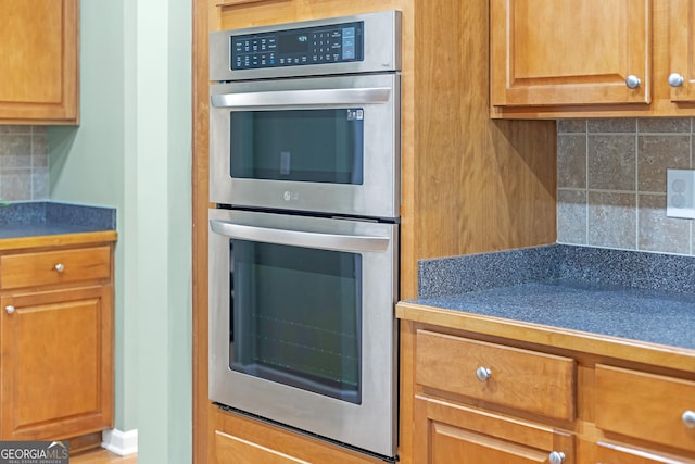 kitchen with brown cabinetry, stainless steel double oven, backsplash, and tile counters