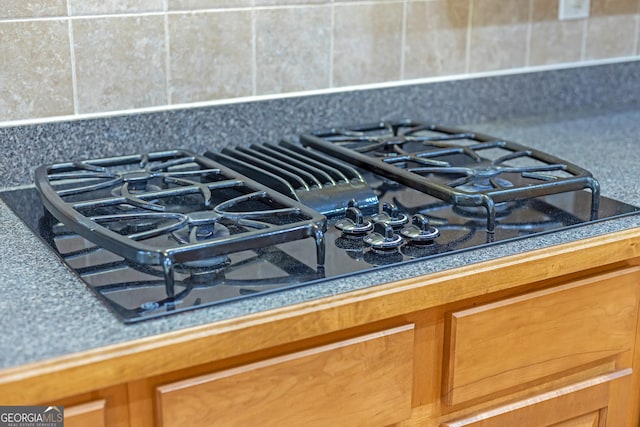 interior details featuring decorative backsplash, brown cabinets, and black gas stovetop