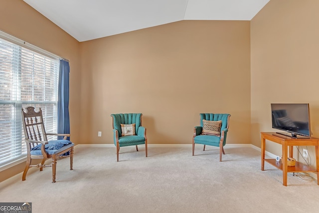 living area featuring lofted ceiling, light carpet, and baseboards