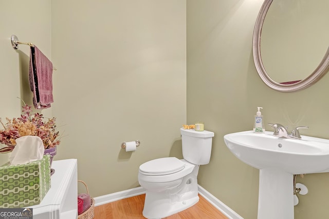 bathroom with baseboards, a sink, toilet, and wood finished floors