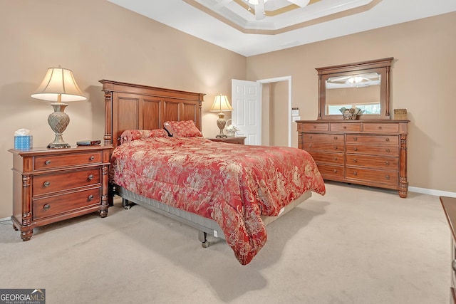 bedroom featuring light carpet, ceiling fan, a tray ceiling, and baseboards