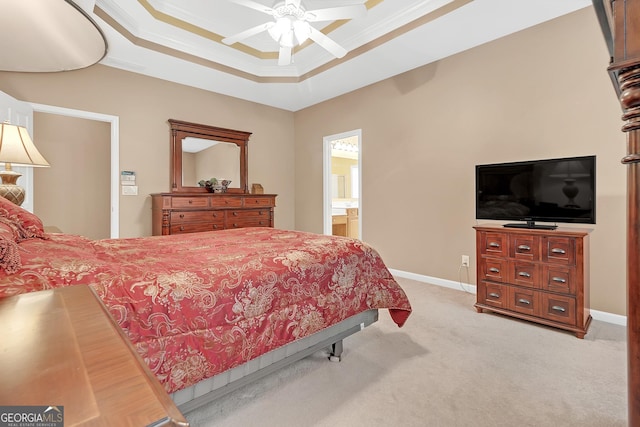 bedroom with baseboards, connected bathroom, light colored carpet, a tray ceiling, and crown molding