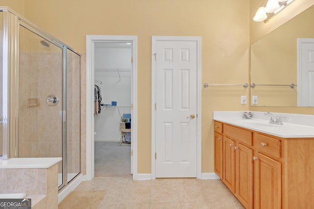 bathroom with a walk in closet, a shower stall, vanity, and tile patterned floors