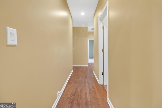 hall featuring light wood-style flooring and baseboards