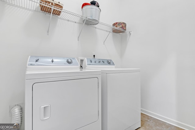 laundry area with baseboards, laundry area, light tile patterned flooring, and washer and dryer