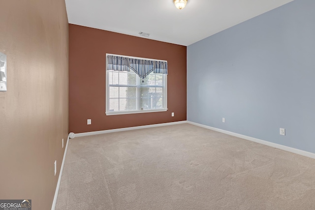 carpeted empty room with visible vents and baseboards