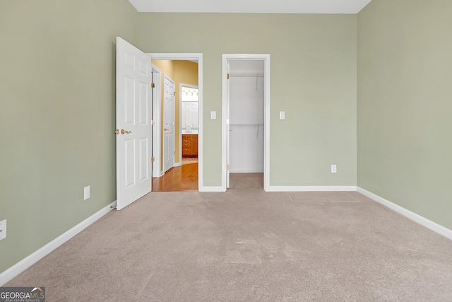 unfurnished bedroom with carpet floors, a spacious closet, baseboards, and a closet