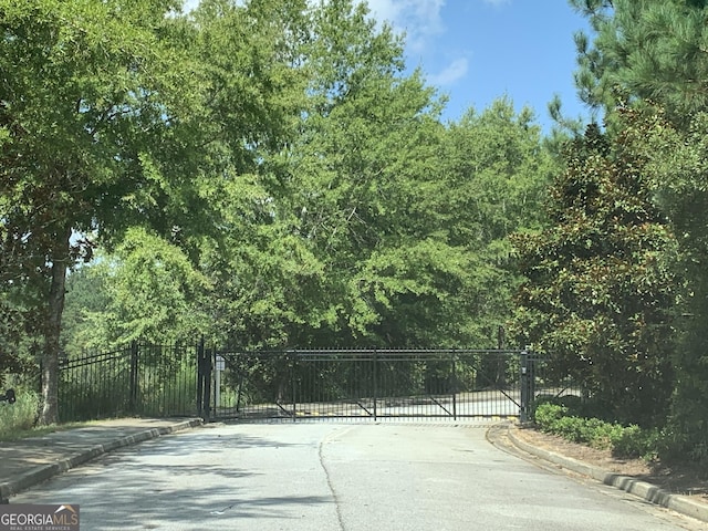 view of road featuring curbs and a gate