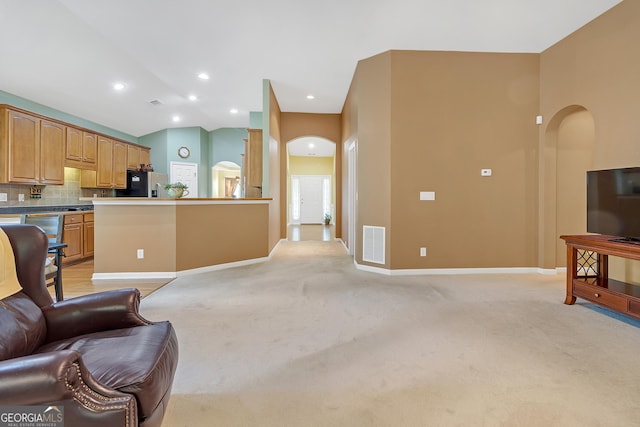 living room featuring light carpet, baseboards, visible vents, arched walkways, and vaulted ceiling