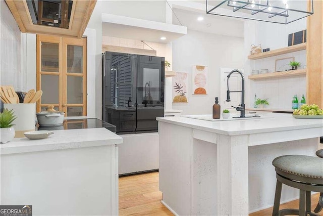 kitchen featuring sink, a kitchen breakfast bar, backsplash, and light hardwood / wood-style floors