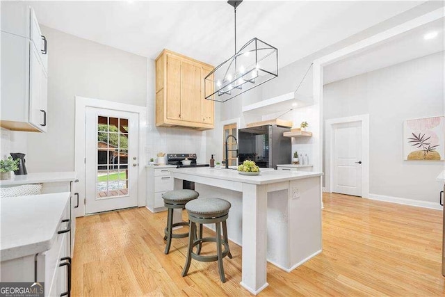 kitchen featuring hanging light fixtures, light hardwood / wood-style floors, a breakfast bar, stainless steel refrigerator, and light brown cabinetry