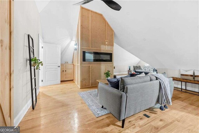 living room with ceiling fan, lofted ceiling, and light hardwood / wood-style floors