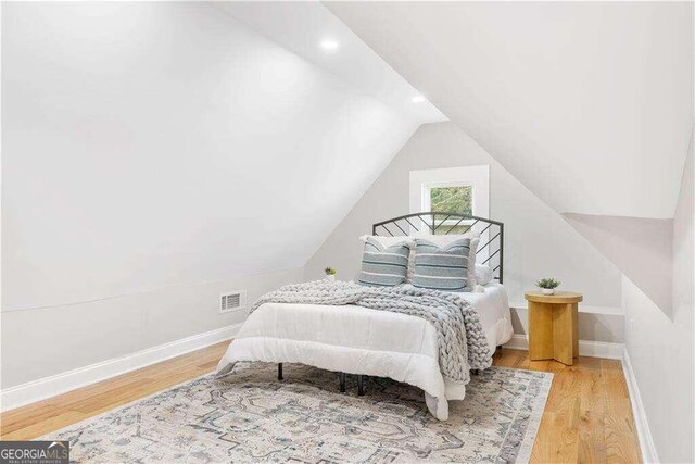 bedroom with light hardwood / wood-style flooring and lofted ceiling